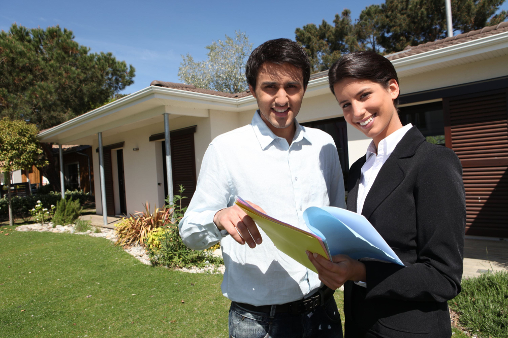 Smiling real estate agent and home owner outside property.